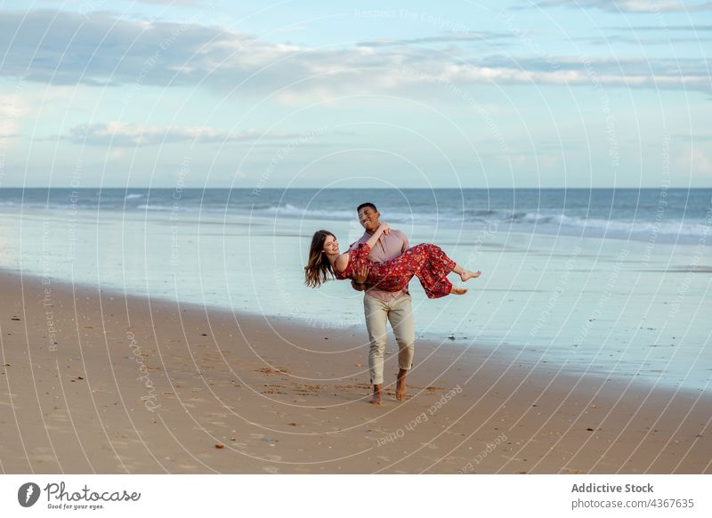 Vergnügtes gemischtrassiges Paar hat Spaß am Strand führen Spaß haben Zusammensein Liebe MEER genießen Meeresufer Sonnenuntergang rassenübergreifend