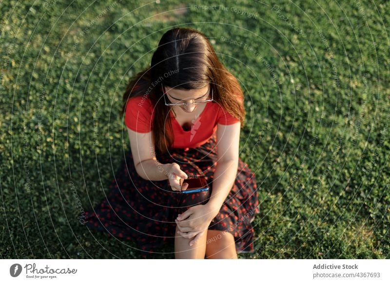 Frau surft auf dem Rasen im Park auf ihrem Smartphone Browsen Wochenende Sommer Abend unterhalten Nachricht benutzend Surfen sich[Akk] entspannen Anschluss