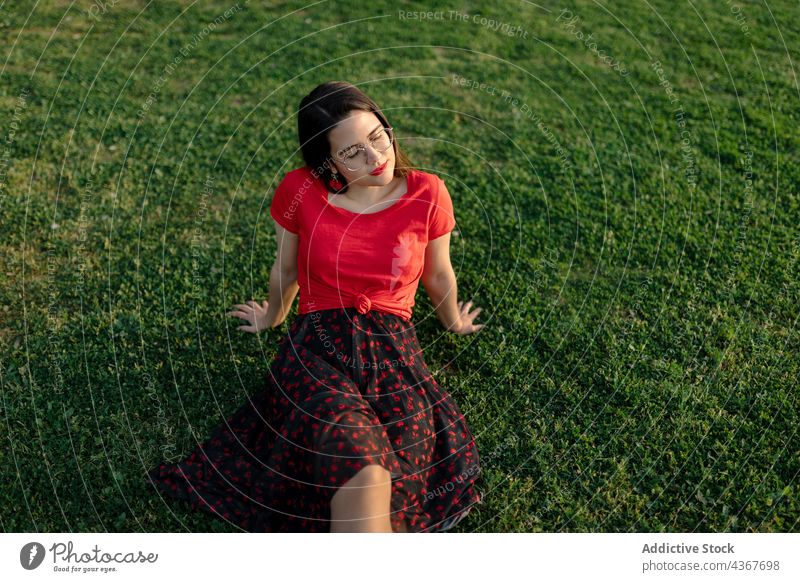 Gelassene Frau chillt auf Rasen im Park Sommer Gelassenheit Harmonie Sonnenuntergang friedlich Wiese genießen Gras Natur Feld sitzen Windstille ruhig sorgenfrei