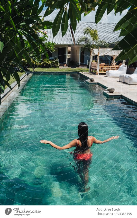 Unerkennbarer Reisender schwimmt im Pool eines tropischen Resorts schwimmen Urlaub Tourismus exotisch Frau Sommer Badeanzug Tourist Natur Architektur Haus