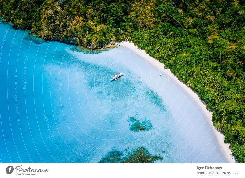 Aerial Top-Down-Ansicht des Bootes an abgelegenen weißen Sandstrand mit Kokospalmen und surreale türkisblaue flache Lagune herum vertäut. Reisen exotisches Paradies Konzept