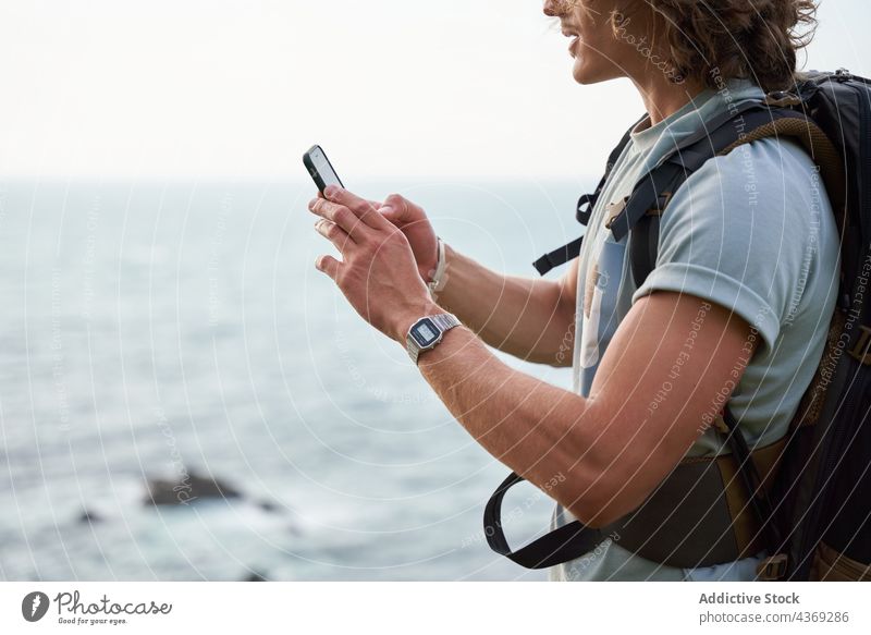 Reisender Mann, der auf einem Hügel gegen das Meer telefoniert Browsen zuschauend Texten Smartphone Trekking heiter reisen Wanderer Sommer fotografieren