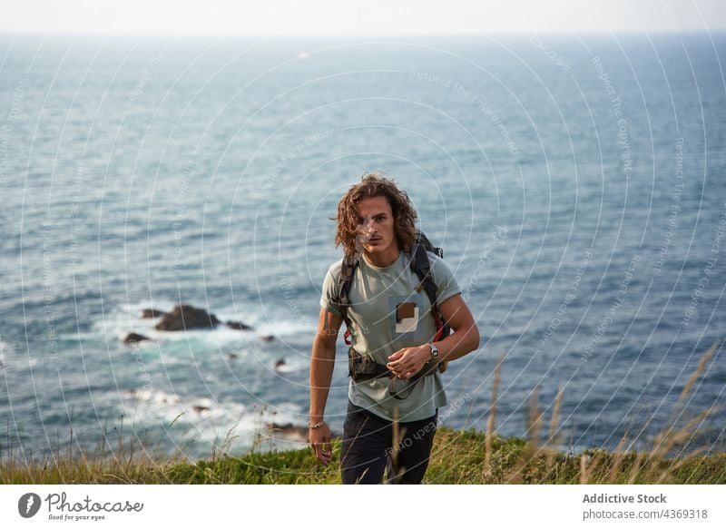 Reisender Mann, der auf einem Hügel gegen das Meer läuft reisen Spaziergang Backpacker Feld Sommer Trekking Freiheit männlich Wiese MEER Wanderung Rucksack