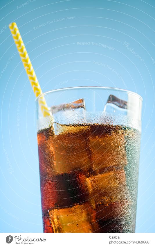 Ein Glas Cola mit Eis auf blauem und rosa Hintergrund Soda weich trinken kalt Stroh Sommer Erfrischung Koffein liquide braun Getränk Kondenswasser Tau Würfel