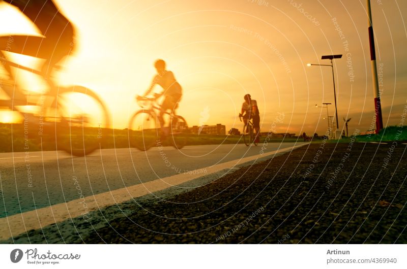 Blur Foto Sport Mann fahren Fahrräder mit Geschwindigkeit Bewegung auf der Straße am Abend mit Sonnenuntergang Himmel. Sommer im Freien Übung für gesunde und glückliche Leben. Radfahrer Reiten Mountainbike auf Radweg. Team.