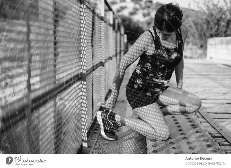 monochromes Bild einer Läuferin, die einen Schuh einstellt Frau Schatten Sport fitte Fitness in voller Länge Frauen Einstellung im Freien Brücke passen