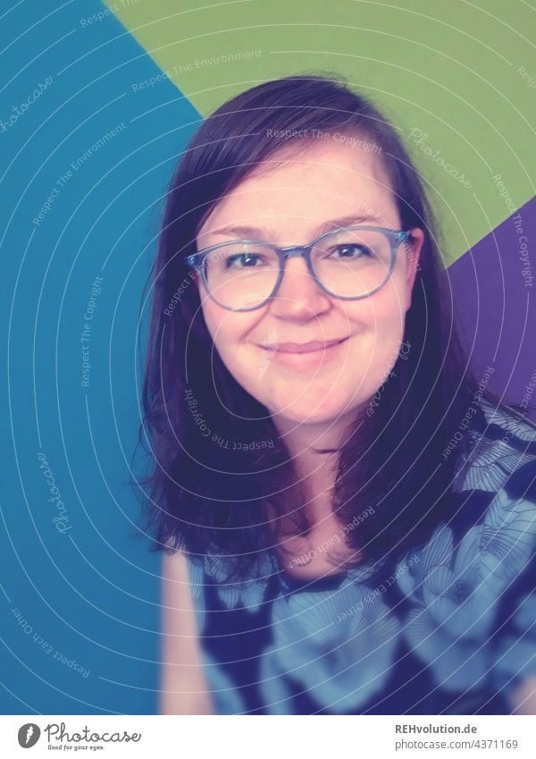 Selfie von einer Frau vor einer bunten Wand Junge Frau langhaarig brünett Brille Vorderansicht Haare & Frisuren Gesicht Porträt Oberkörper Erwachsene Mensch