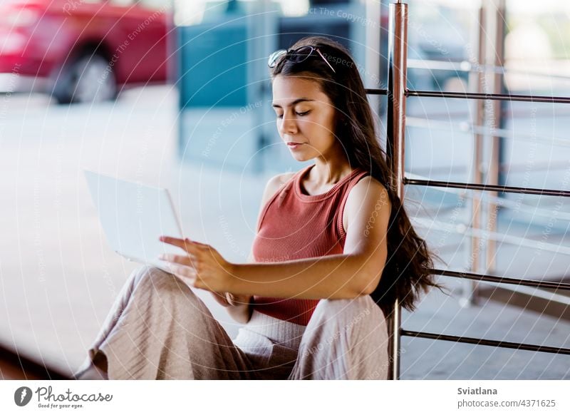 Porträt einer Studentin, die auf einer städtischen Treppe sitzt und im Freien einen Laptop benutzt Mädchen Sitzen benutzend Schüler Bildung lesen Campus