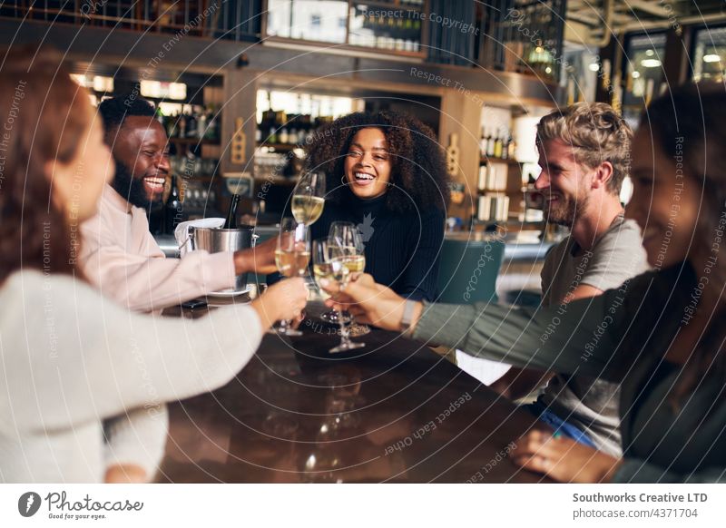 Freunde feiern mit Wein in einer Bar Zuprosten Feier Frau Mann jung Menschengruppe sozialisierend im Innenbereich Tag Veranstaltungsort fünf multiethnisch