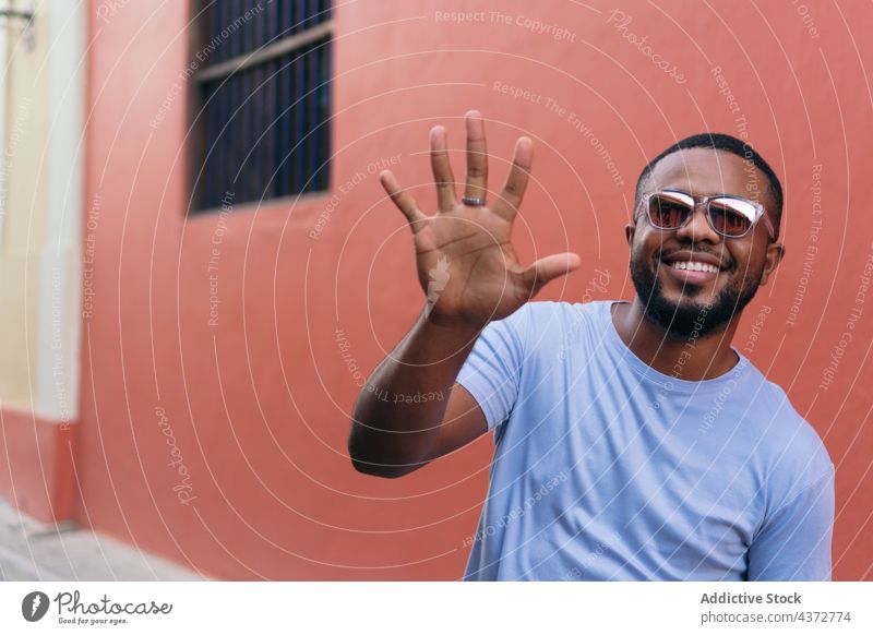 Lächelnder afrikanischer Mann zeigt seine Hand beim Spaziergang im Freien selbstbewusst männlich Erwachsener Afrikanisch Amerikaner schwarz Ethnizität