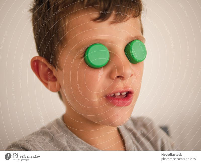 Junge mit Plastikdeckeln auf den Augen Verschlussdeckel Deckel Top lustig bedeckt Porträt abschließen Kaukasier Spaß Genuss gestikulieren Ausdruck lässig Kind