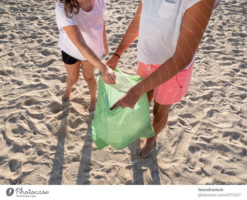 zwei Mädchen sammeln Plastik am Strand, keine Gesichter gezeigt umgebungsbedingt Tasche Kommissionierung zu picken Kunststoff Umwelt Menschen Ökologie männlich