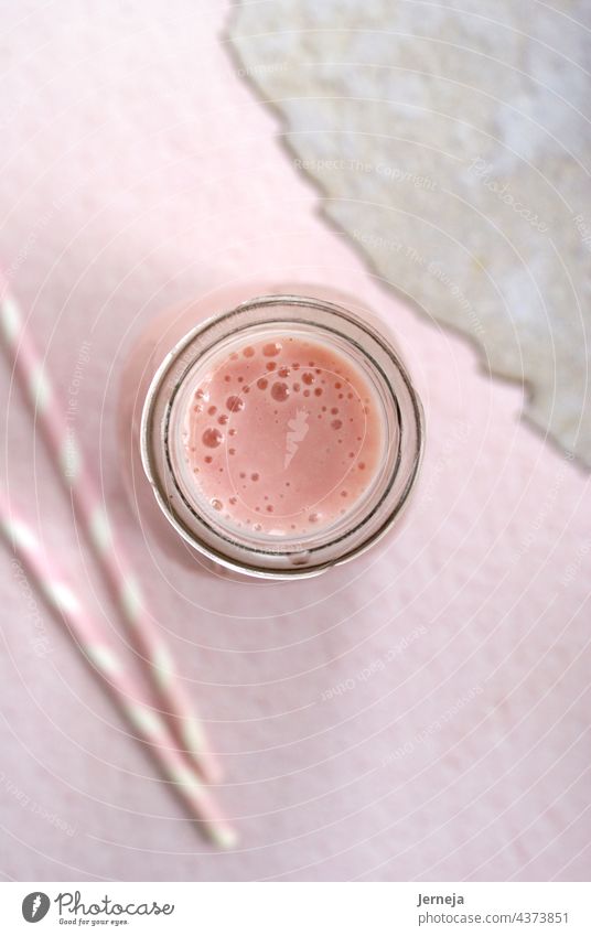Erdbeer-Smoothie in einer Flasche mit rosa Hintergrund und rosa Papierstrohhalmen. Milchshake melken Gesundheit Erdbeeren Entzug Glas Frucht Beeren Joghurt