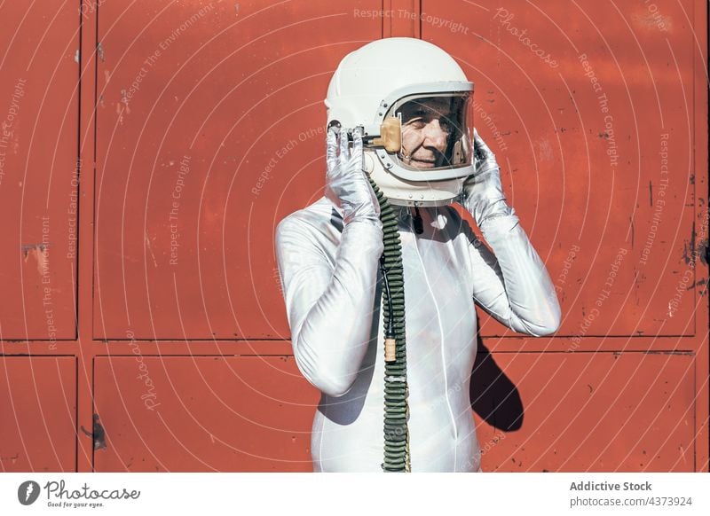 Astronaut steht vor einem Industriegebäude Mann rot Wand Einrichtung Raumanzug Konzept Uniform futuristisch Wissenschaft männlich Entwicklung Missionsstation