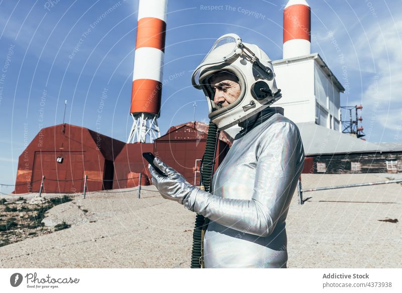 Älterer Kosmonaut bei der Benutzung eines Mobiltelefons Mann Smartphone benutzend Einrichtung Weltraumbahnhof Konzept Raumanzug Daten Industrie männlich behüten