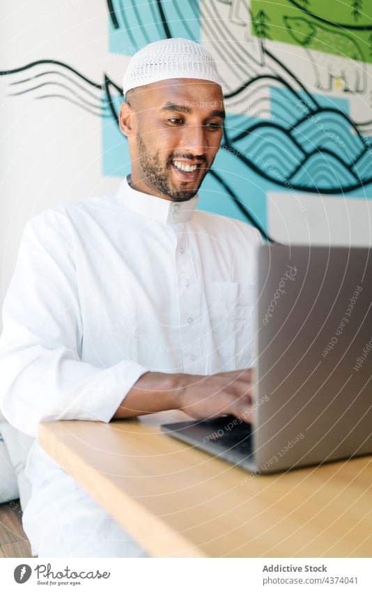 Islamischer Mann benutzt Laptop in einem Cafe benutzend Café Lächeln ruhen Wochenende soziale Netzwerke Tippen authentisch männlich freiberuflich Daten Browsen