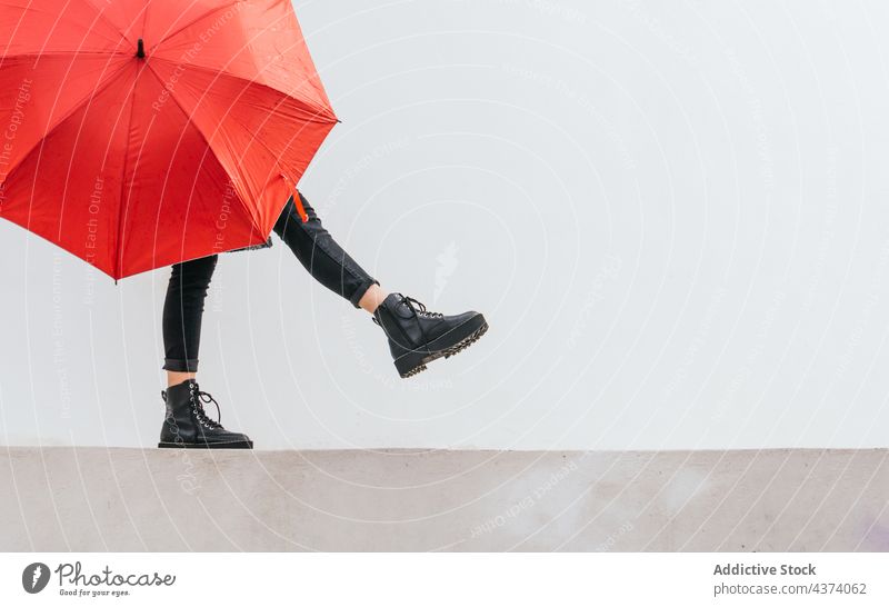 Anonyme junge Frau mit Regenschirm, die auf der Grenze balanciert Gleichgewicht Spaziergang Borte Straße Glück Wetter urban Großstadt Herbst heiter lässig