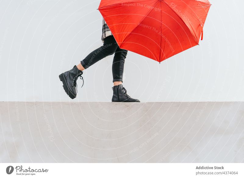 Anonyme junge Frau mit Regenschirm, die auf der Grenze balanciert Gleichgewicht Spaziergang Borte Straße Glück Wetter urban Großstadt Herbst heiter lässig