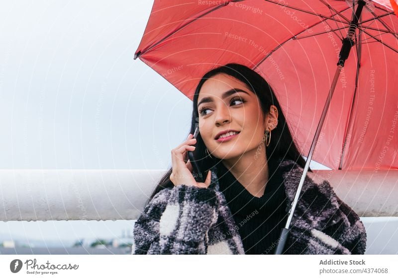 Junge Frau benutzt Smartphone an einem regnerischen Tag benutzend Straße Regen Regenschirm nass ruhen Wetter Stil ethnisch jung urban Großstadt Browsen Gerät