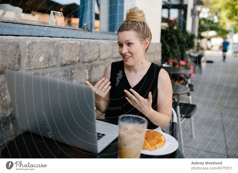 Junge berufstätige Frau bei einer Telefonkonferenz in einem Café im Freien 25-30 30-35 Jahre Erwachsener Amerikaner Blogger blond Chef Kaukasier Kaffee