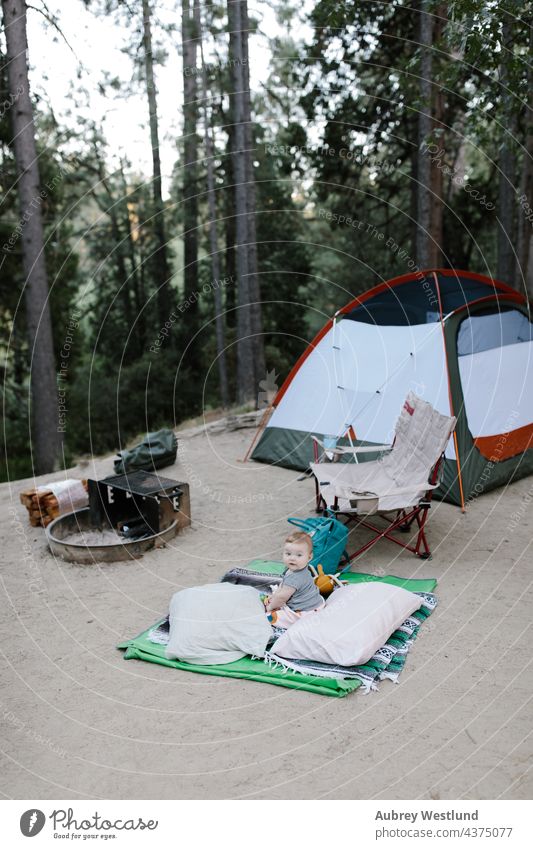 Baby auf dem Boden eines Zeltplatzes sitzend Kalifornien Lager Wohnmobil Camping Campingplatz Stuhl Kind Kindheit Tochter Familie Feuer Wald Spaß Mädchen Glück
