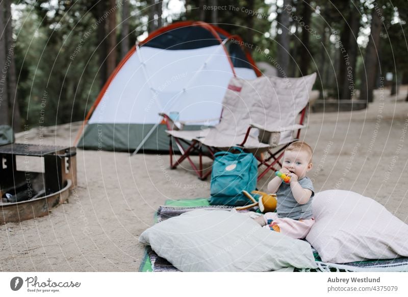 Baby spielt auf dem Boden eines Zeltplatzes 6 Monate Kalifornien Lager Wohnmobil Camping Campingplatz Stuhl Kauen Kind Kindheit Tochter Essen Familie Feuer Wald