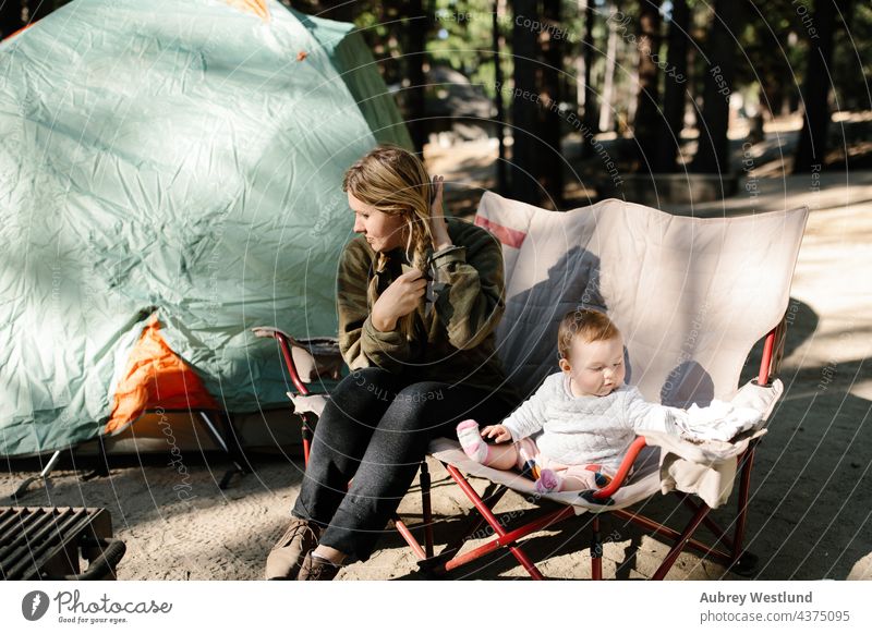 Mutter und ihr kleines Mädchen sitzen auf einem Campingstuhl beim Zelten im Freien Baby blond Kalifornien Lager Campingkocher Wohnmobil Campingplatz Kaukasier