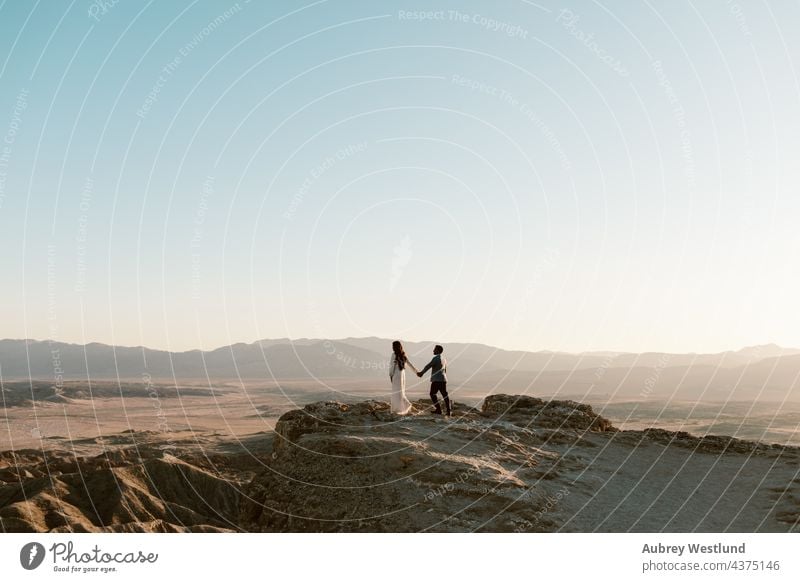 Mann und Frau halten sich an einem Aussichtspunkt in der Wüste an den Händen anza-borrego-wüste Ödland Kakteen Kaktus Paar kostümiert Erosion Schriftarten Punkt