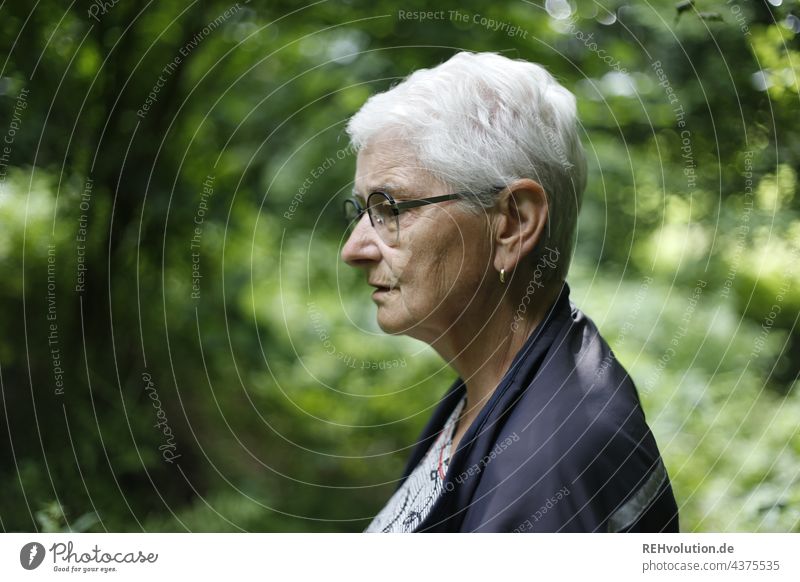 Profil von einer Seniorin im Wald 60 und älter Weiblicher Senior Großmutter grauhaarig natürlich weißhaarig Frau Porträt authentisch Brille Natur Landschaft