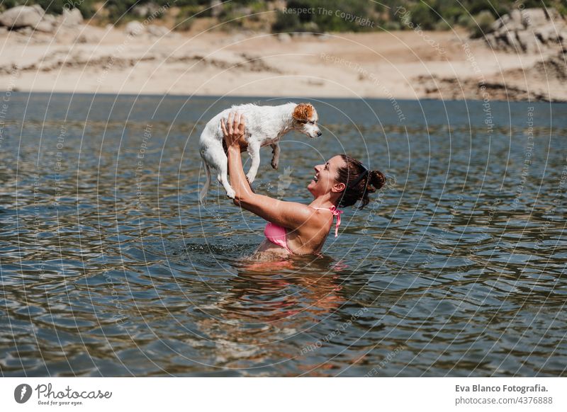 kaukasische Frau und niedlichen Jack Russell Hund schwimmen im See und Spaß haben zusammen. Urlaub und entspannen Konzept jack russell Schwimmsport Natur Sommer