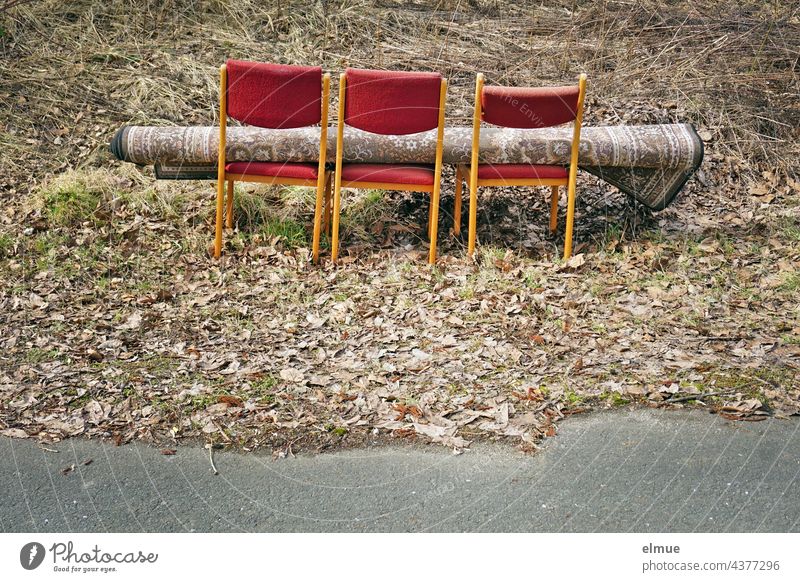 drei Stühle und ein darauf liegender Teppich mitten in der Natur neben einer Straße / illegale Müllentsorgung Sperrmüll Sperrmüllentsorgung Naturverschmutzung