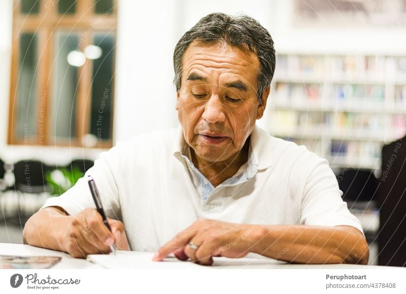 Ernster älterer Mann sitzt auf einer Bibliotheksbank und schreibt in sein Buch. schreibend Klassenraum Bildung Lernen Notizen Wissen Lifestyle Menschen Person