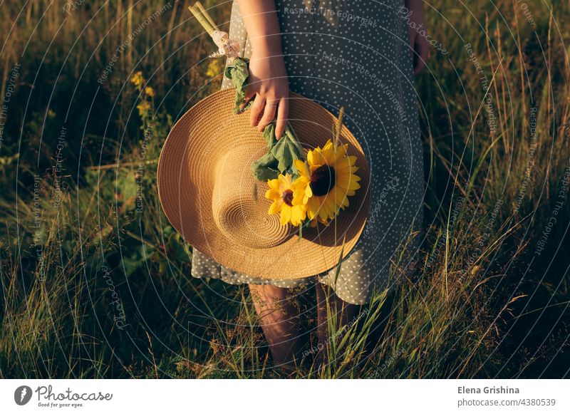 Das Mädchen hält einen Hut und einen Strauß Sonnenblumen in den Händen. Sommer Gras Feld Sonnenuntergang Verlangsamung Stille Naturverbundenheit natürlich