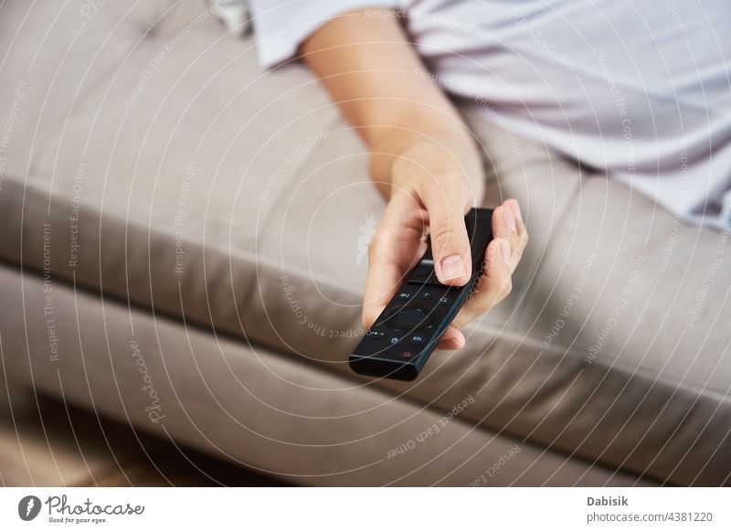 Frau schaltet mit der Fernbedienung des Fernsehers die Kanäle um. FERNSEHER zuschauen Fernsehen abgelegen Kontrolle lebend sich[Akk] entspannen Hand zuschauend
