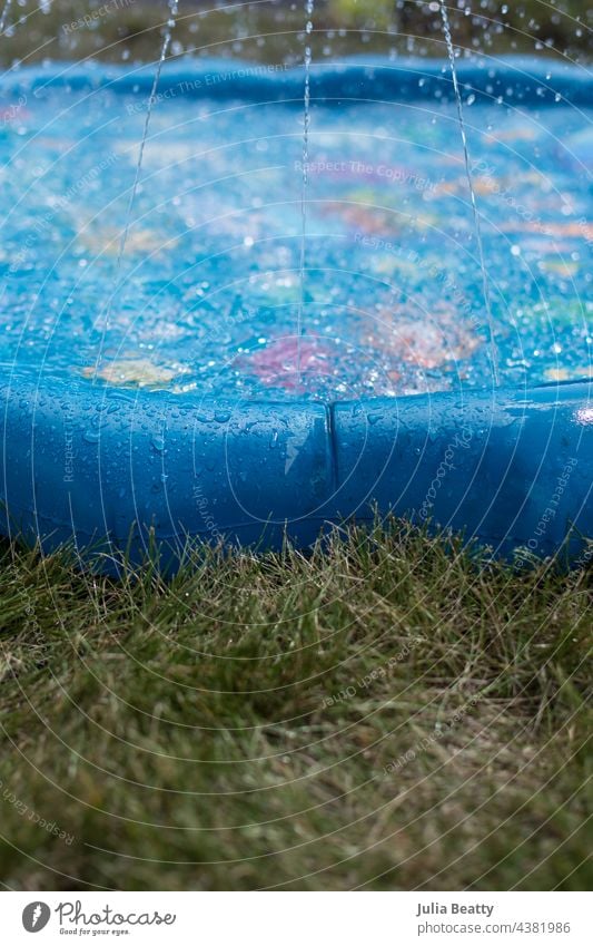 Aktivität an einem heißen Sommertag; Wasser im Planschbecken, Sprinkler, Spielzeug im Gras Sprinkleranlage Pool Baby-Pool waten Spray Vinyl aufblasen Wasserpark