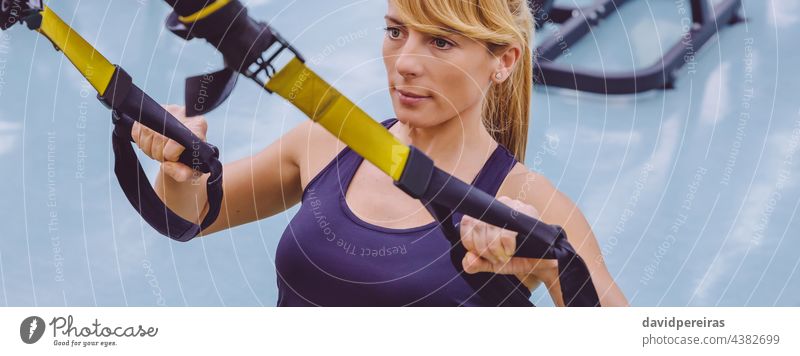 Frau beim Suspensionstraining mit Fitnessgurten Panorama Transparente trx Sportlerin Fitnessstudio Training Gurt Textfreiraum Mädchen Athlet Kaukasier