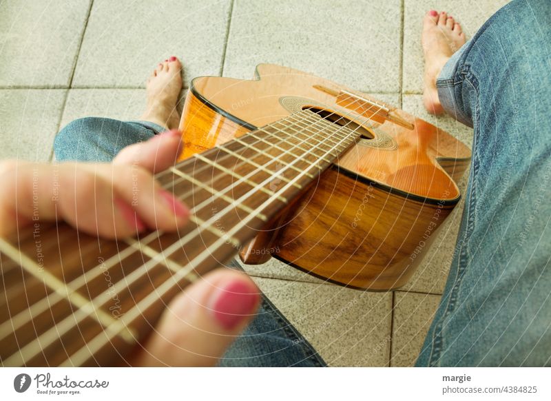Eine Frau spielt barfuß Gitarre Musik Saite Detailaufnahme Fuß Barfuß Saiteninstrumente Musikinstrument Freizeit & Hobby Nahaufnahme Schwache Tiefenschärfe