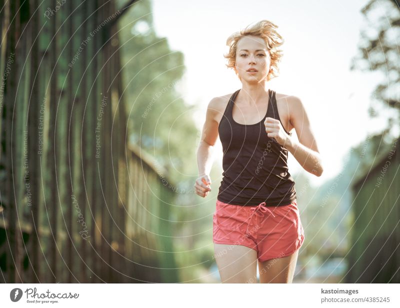 Athleten laufen auf railaway Brücke Training für Marathon und Fitness. Gesunde sportliche kaukasische Frau, die in städtischer Umgebung trainiert, bevor sie zur Arbeit geht. Aktiver städtischer Lebensstil