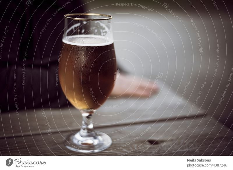 glas bier mit tau auf holztisch. unscharfe menschliche silhouette dahinter Bar Bier Glas Wasser Tropfen frisch Frische Alkohol Getränke trinken Erfrischung