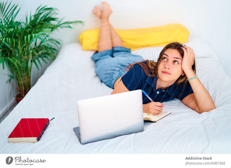 Junge Frau studiert online im Schlafzimmer Schüler schreiben Laptop Bett lernen zu Hause abgelegen Bildung Apparatur jung Teenager zur Kenntnis nehmen Internet