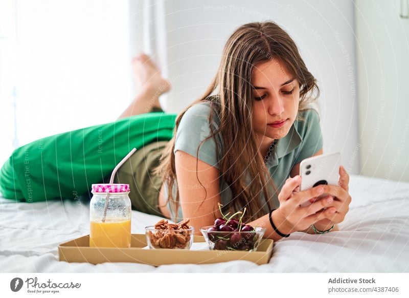 Junge Frau benutzt Smartphone beim Frühstück benutzend zu Hause Morgen online Browsen Internet Kommunizieren jung Schüler Mobile Apparatur Gerät Telefon Surfen