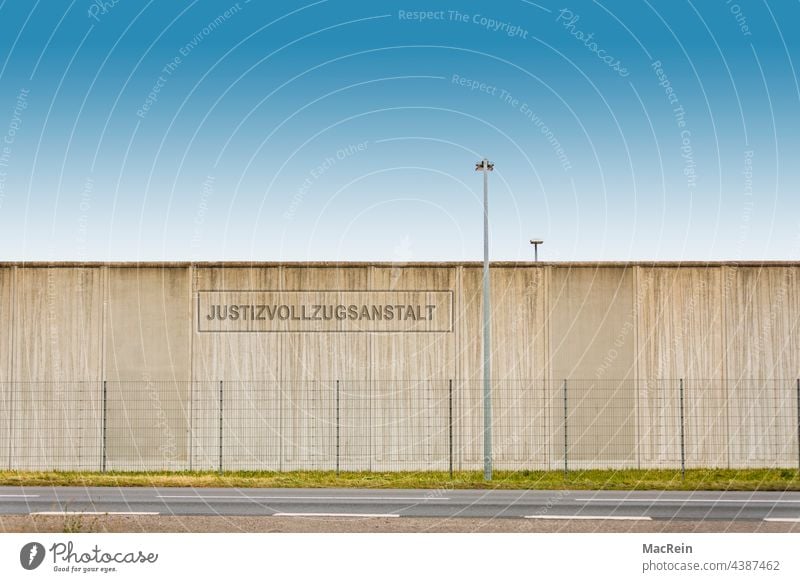 Gefängnismauer einer Justizvollzugsanstalt Aussenaufnahme Absperrung Drahtzaun Eingesperrt Haft Haftanstalt Kein Mensch Laterne Mauer NIemand Strasse