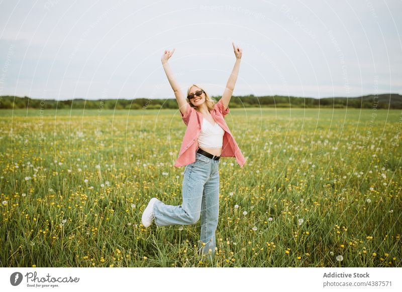 Fröhliche Frau, die im Sommer auf einem Feld ein Horn zeigt Felsen gestikulieren Hupe Zeichen Rock and Roll heiter Wiese Freiheit sorgenfrei zeigen Stil Glück