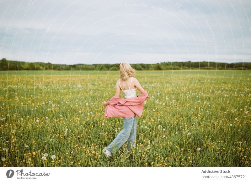 Unerkennbare unbekümmerte Frau, die in einem blühenden Feld spazieren geht Sommer sorgenfrei Freiheit Wiese Blütezeit Blume Spaziergang genießen Natur