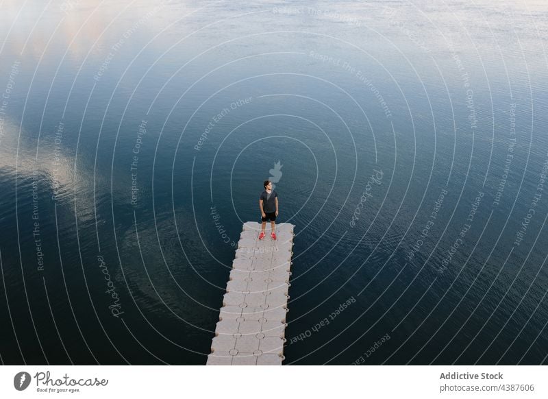 Mann steht am Pier in der Nähe des Sees Windstille Teich Kai Ufer Gelassenheit friedlich ruhig männlich Natur Wasser Küste Saum stehen malerisch