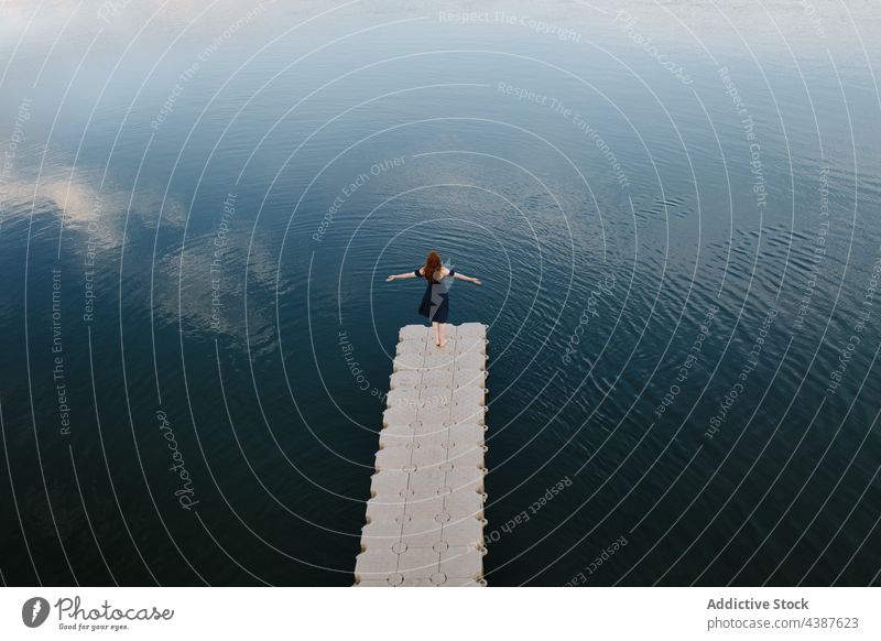 Unbekümmerte Frau steht auf einem Pier in der Nähe eines Teiches See sorgenfrei Freiheit ausdehnen Kai genießen Gelassenheit Wasser ruhig bewundern Ufer Saum