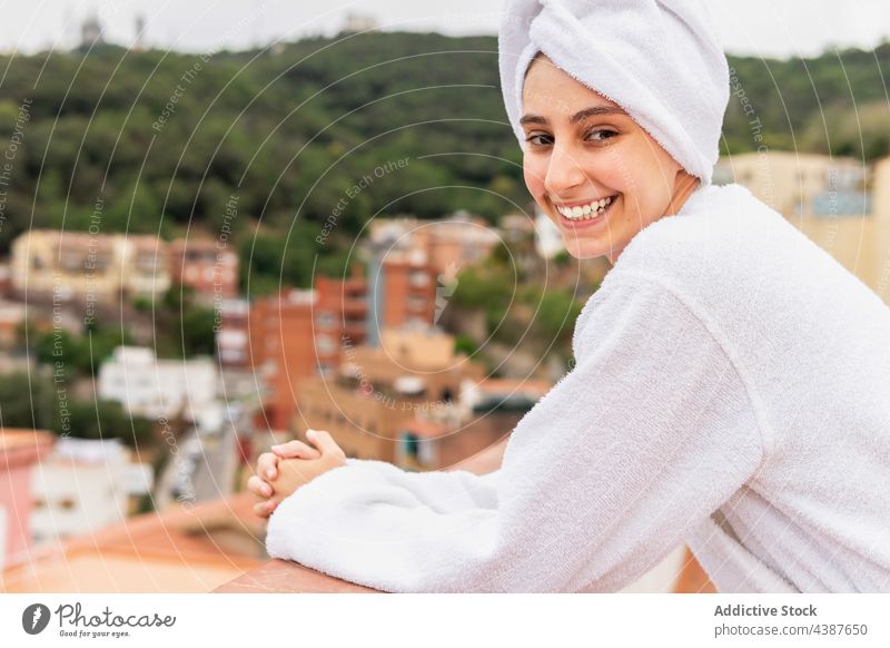 Fröhliche Frau ruht sich nach dem Duschen auf dem Balkon aus ruhen Hautpflege Routine Wochenende Hygiene Lächeln Morgen jung heiter Verfahren Spa Handtuch