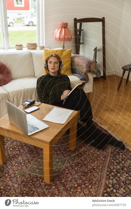 Frau mit Kopfhörern, die Notizen macht und einen Podcast aufnimmt Aufzeichnen Radio Wirt zur Kenntnis nehmen schreiben Notebook Konzentration nachdenklich