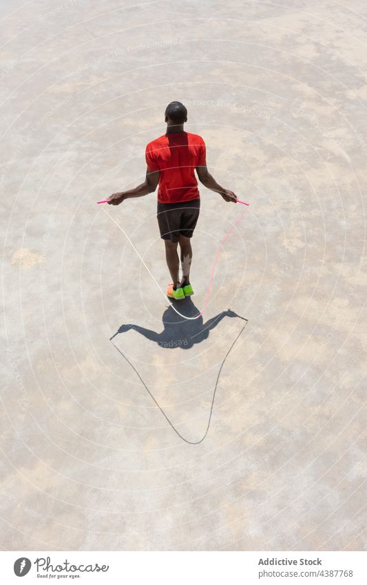 Unbekannter schwarzer Sportler beim Seilspringen auf dem Sportplatz Hüpfseil Training Übung überspringen Athlet aktiv männlich ethnisch Afroamerikaner Mann