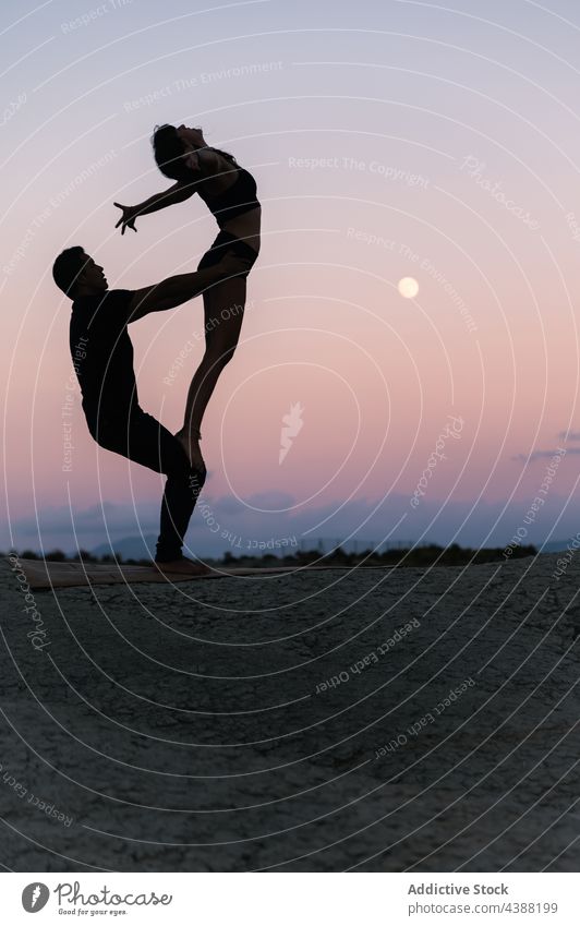 Silhouette von Paar tun acroyoga gegen Sonnenuntergang Himmel Akro-Yoga Gleichgewicht Partner Zusammensein üben akrobatisch Händchenhalten Pose abstützen Abend